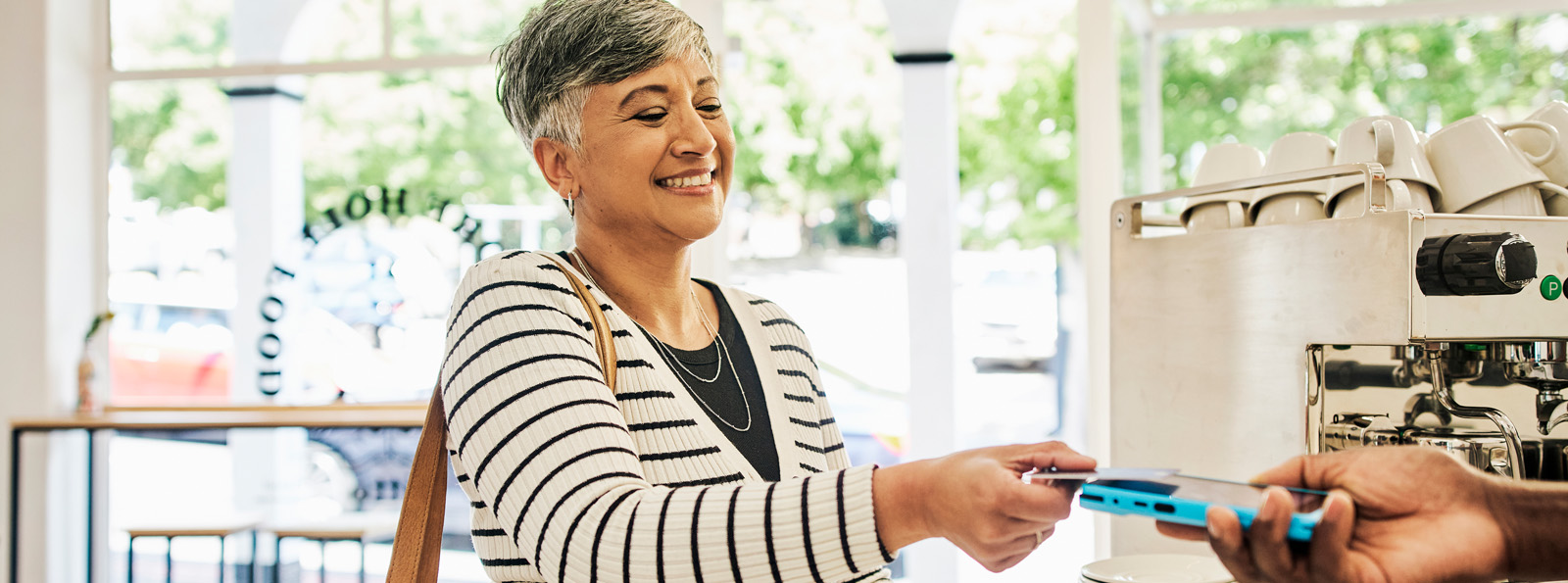 Image of smiling woman holding a credit card making a purchase.