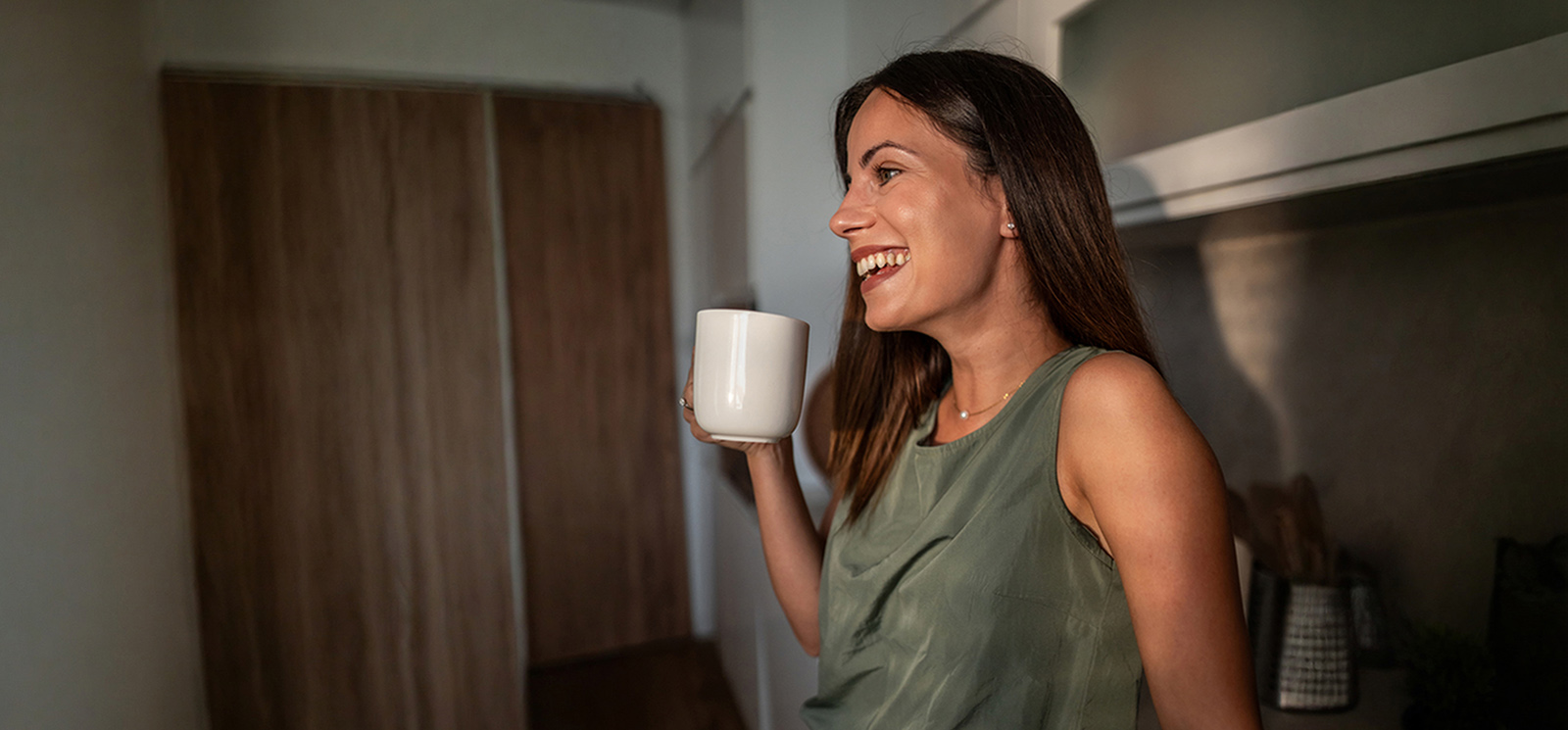 Smiling woman holding a coffee mug.