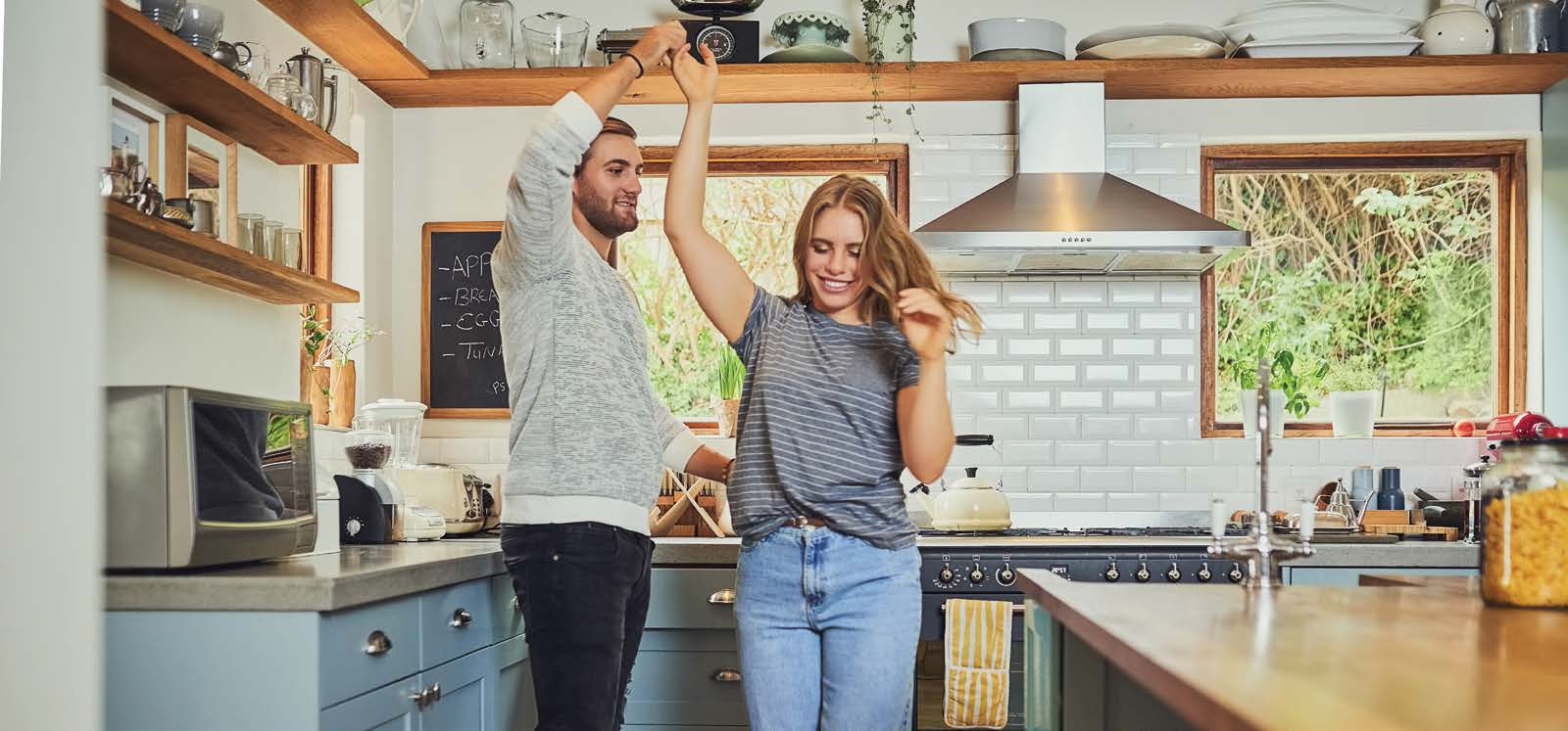 Smiling couple dancing in kitchen.