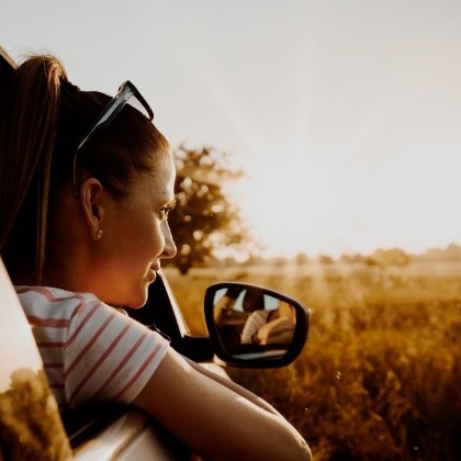 a woman looking at a sunset out the window of an automobile